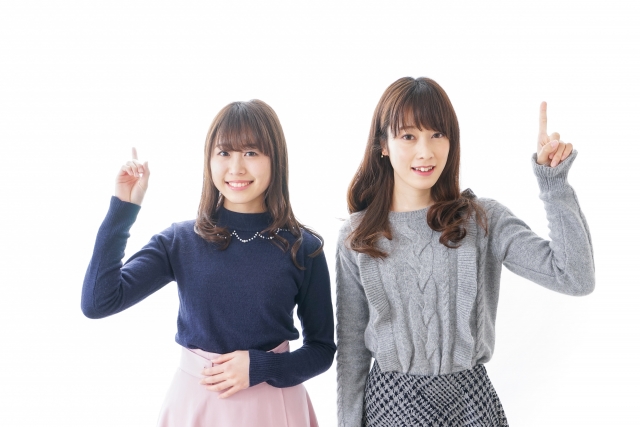 笑顔で指を指す二人の若い女性